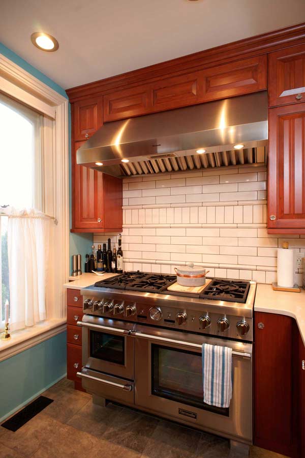 traditional blue kitchen with stainless thermador range and white tile backsplash designed by morris black designs