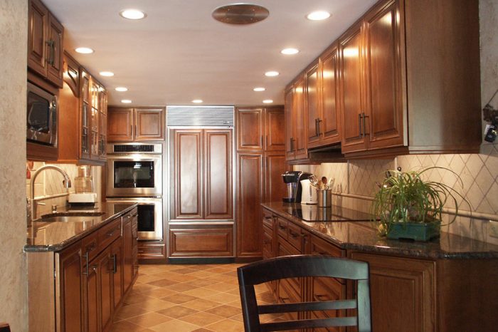 traditional galley kitchen with double wall ovens and cherry kraftmaid kitchen cabinets designed by morris black