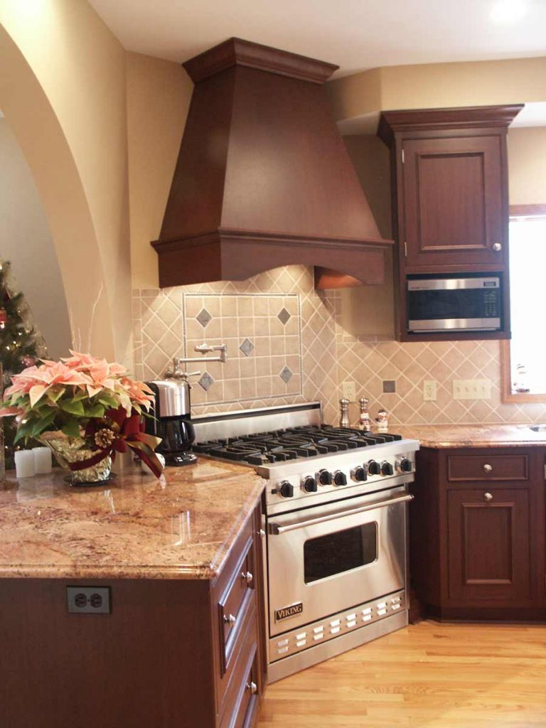 mediterranean kitchen with a custom rangehood and stainless steel appliances