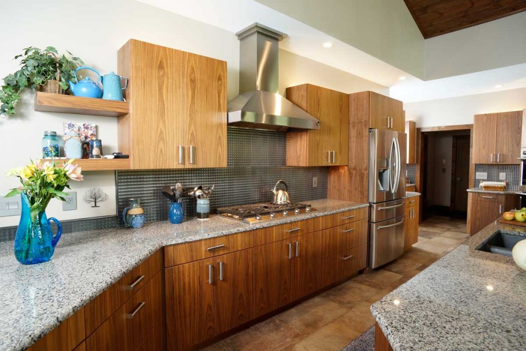 walnut cabinetry and stainless steel appliances in stone kitchen